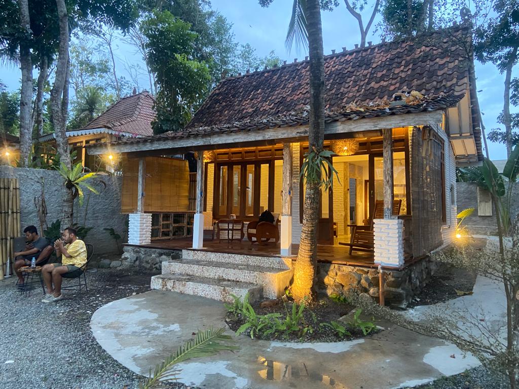 Teras kayu SARÉ Bangunjiwo menyala hangat saat senja