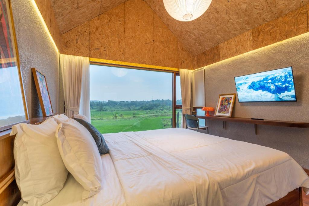 Kamar Tree House SARÉ dengan langit-langit kayu dan jendela menghadap sawah